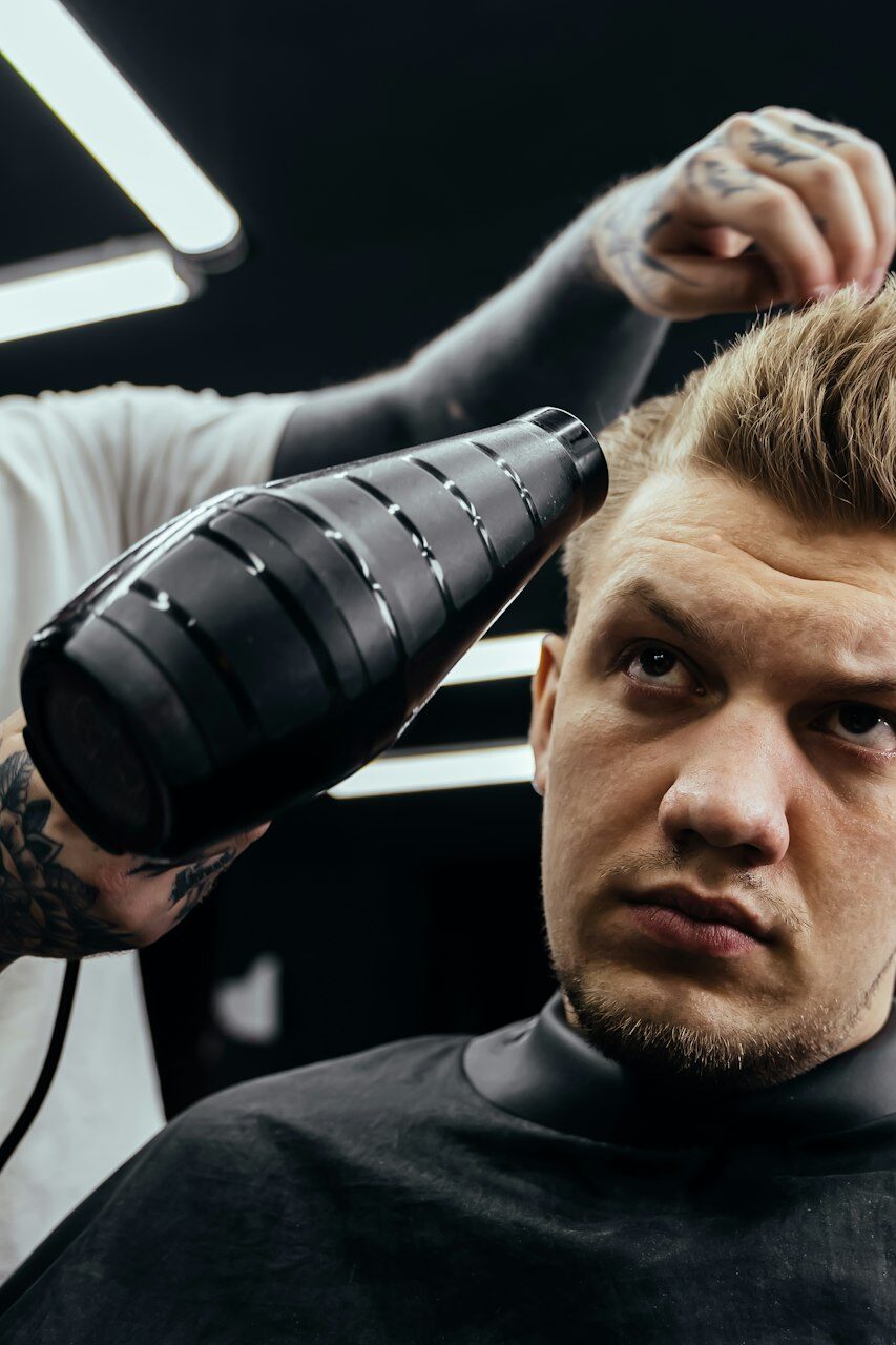 Barber drying male hair in hairdressing salon